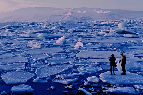 Двама души, които стоят върху топящ се лед в Северна Исландия