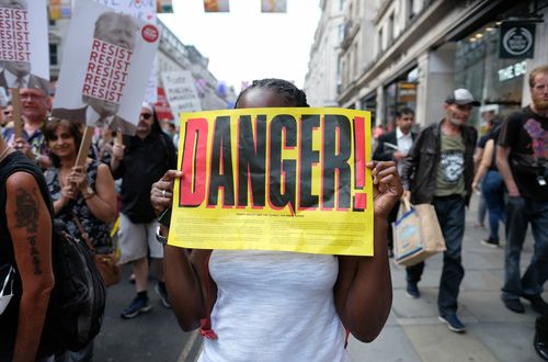 Протестиращо момиче държи надпис „Опасност“