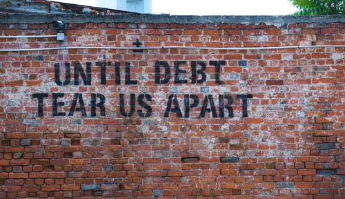 Графит на тухлена стена „Докато дълговете ни разкъсат“