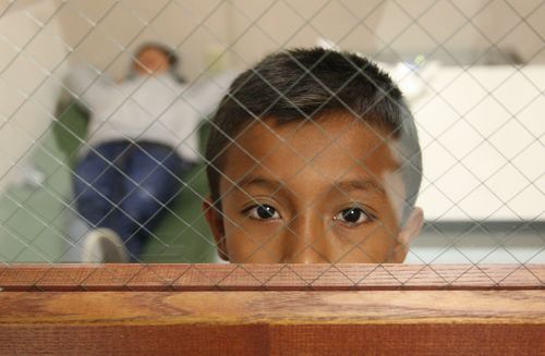 Малко момче гледа през решетки в бежански център в САЩ