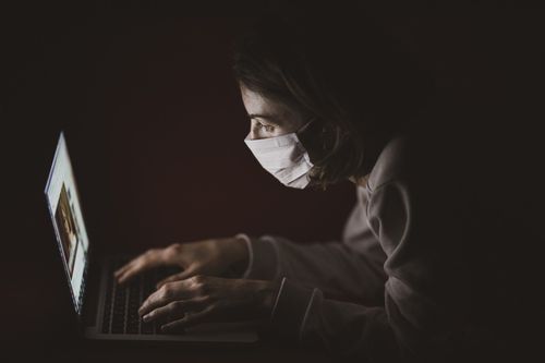 Жена стои с маска пред компютър
