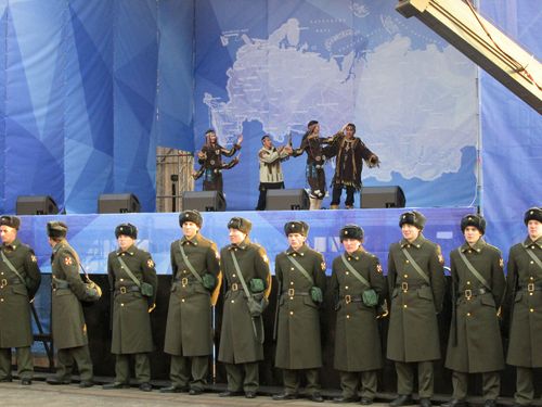 Сцена с актьори в народни носии на фона на картата на Русия; редица от руски войници пред сцената