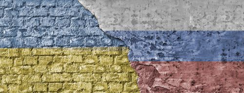 Ронеща се тухлена стена с флаговете на Украйна и Русия