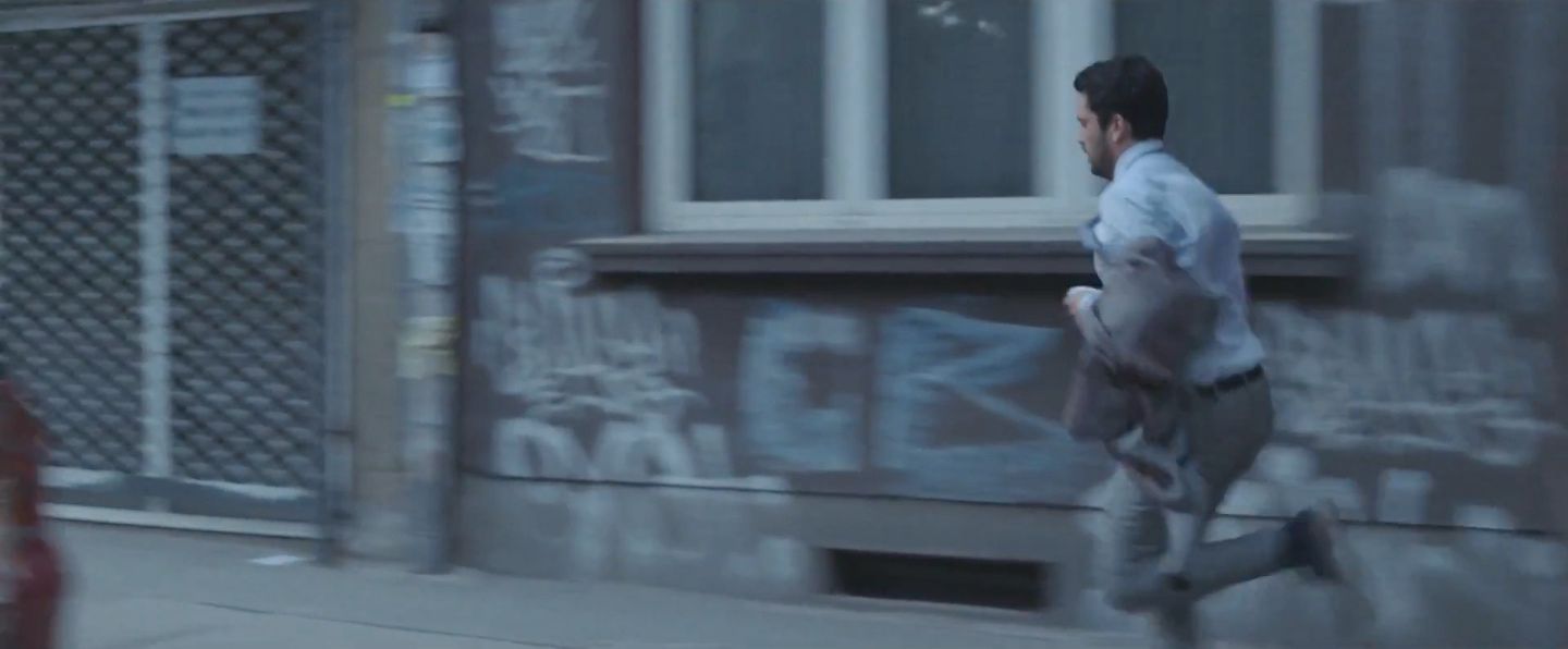Един от главните герои тича по улици с надраскани с графити фасади на сгради